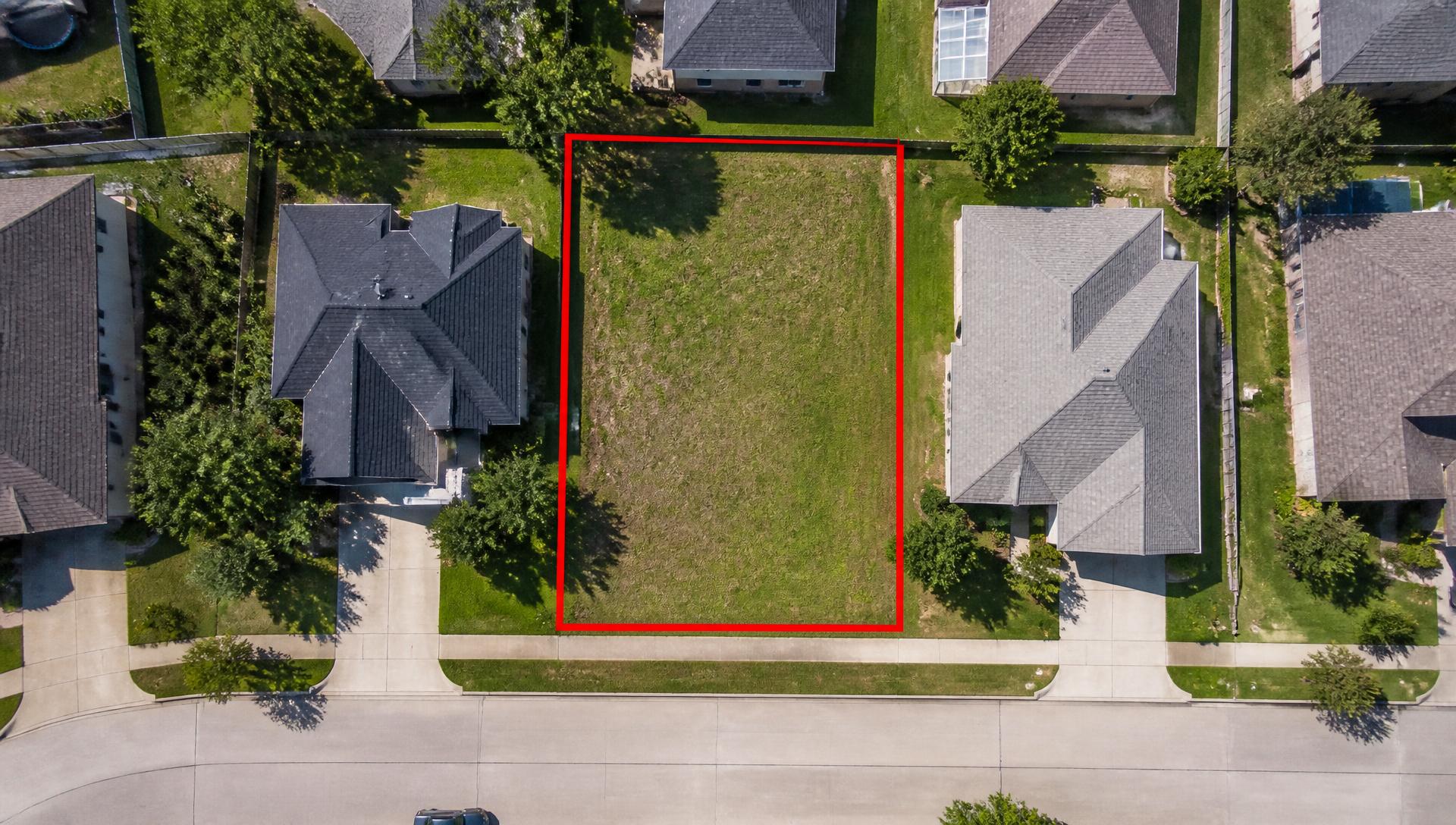 Overhead aerial view of a vacant infill lot outlined in red, surrounded by subdivision homes
